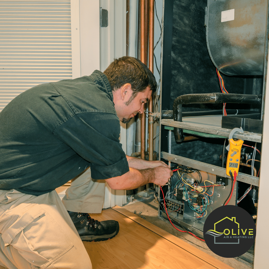 Technician from Olive Air repairing electrical control failures in an AC unit, a frequent issue among common AC problems.