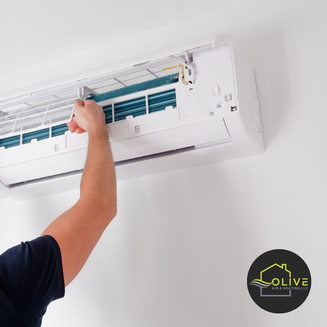 An HVAC technician inspecting the internal components of an AC unit, checking for wear, damage, and potential issues during a routine maintenance session.