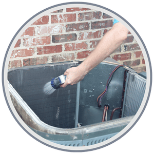 HVAC technician carefully cleaning the outdoor coil of an air conditioning unit