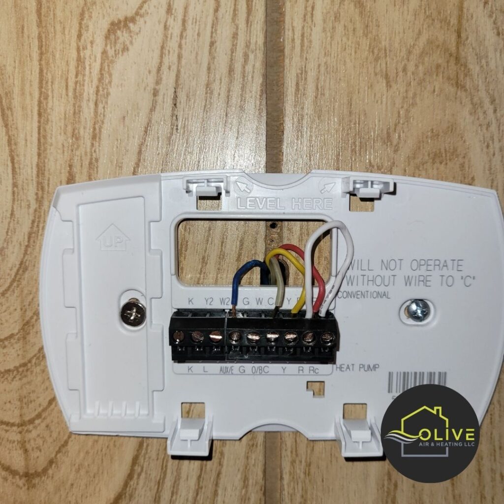 A close-up of a complex thermostat wiring setup, highlighting the potential risks of attempting DIY wiring and installation. AC and Heating Tune Up