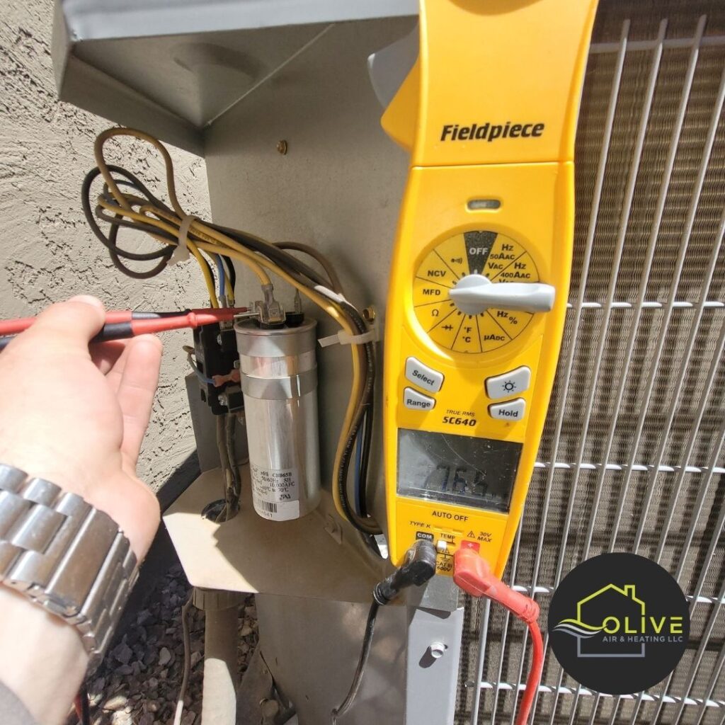 A technician using a multimeter to test the voltage across an AC capacitor during a routine tune-up. This is a crucial step in ensuring the proper functioning of the AC system. Ac and Heating tune Up