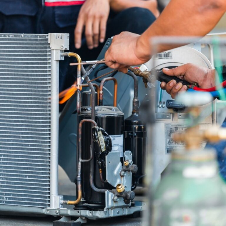 A technician repairing an air conditioning unit, highlighting the expertise and quality service offered for Heating Repair Services in Phoenix.