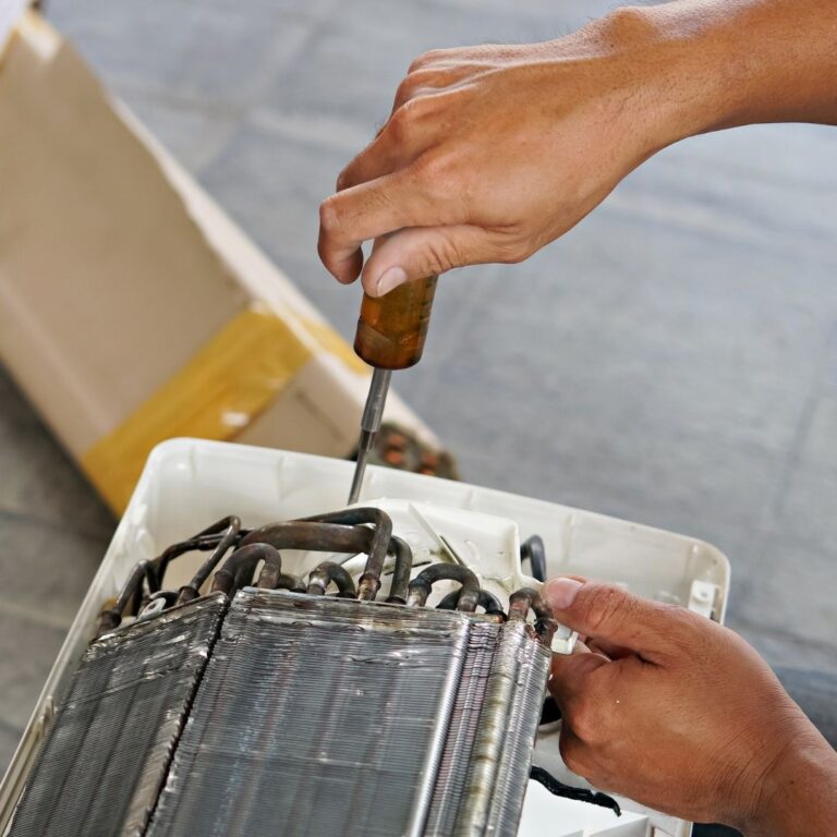 A technician inspecting and cleaning the evaporator coils of a heat pump system as part of professional Heat Pump Services in Goodyear.