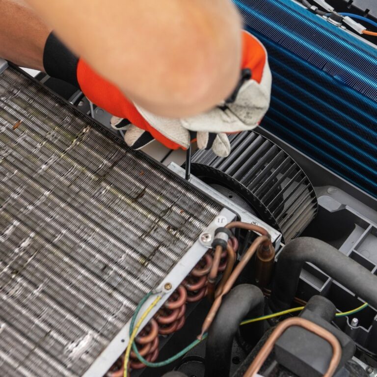 A technician inspecting and cleaning the evaporator coil of a heat pump system as part of professional Heat Pump Services in Mesa.